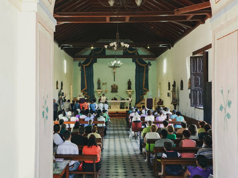 A full congregation participates in a Catholic mass at a traditional church.