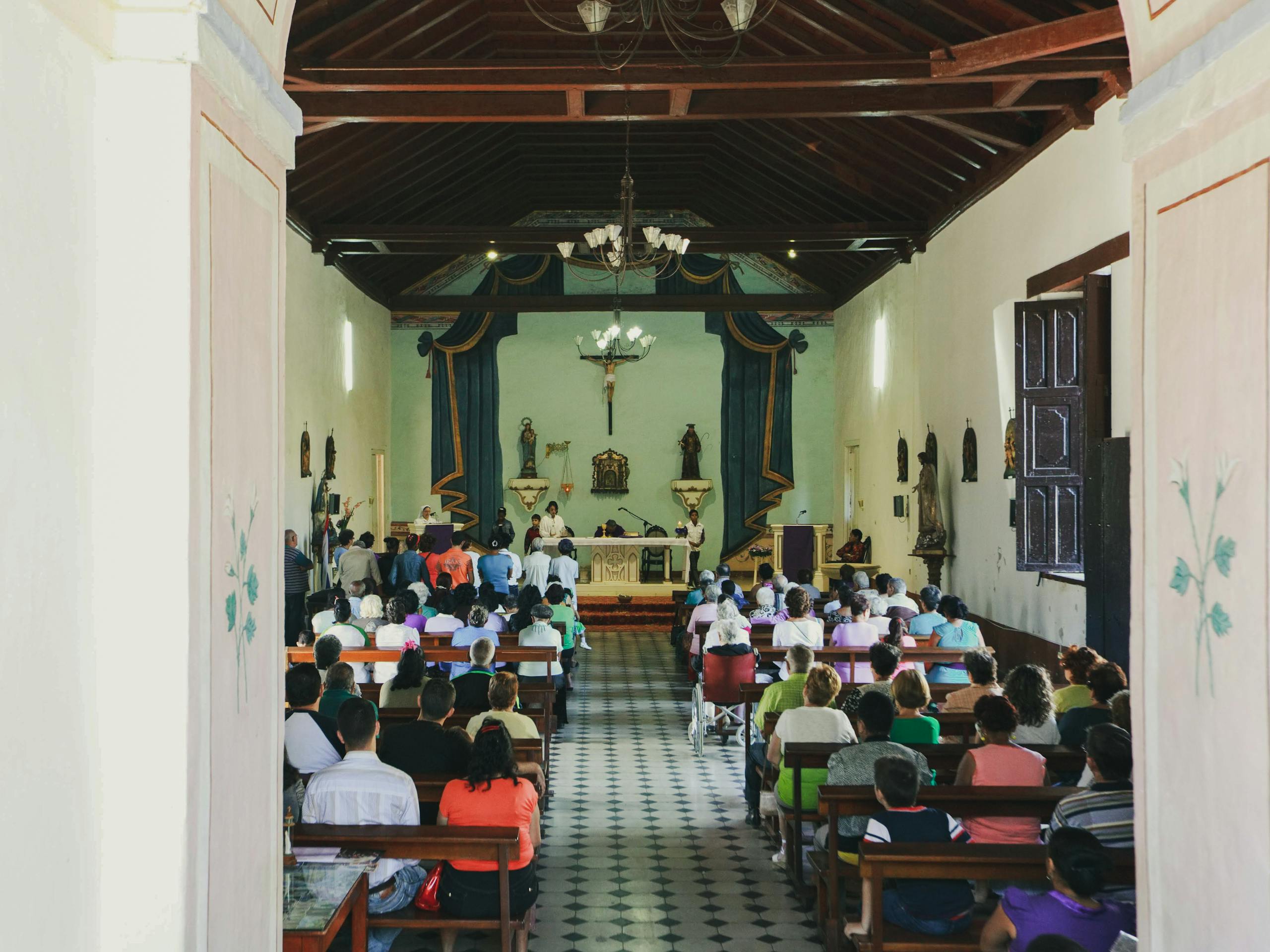 A full congregation participates in a Catholic mass at a traditional church.