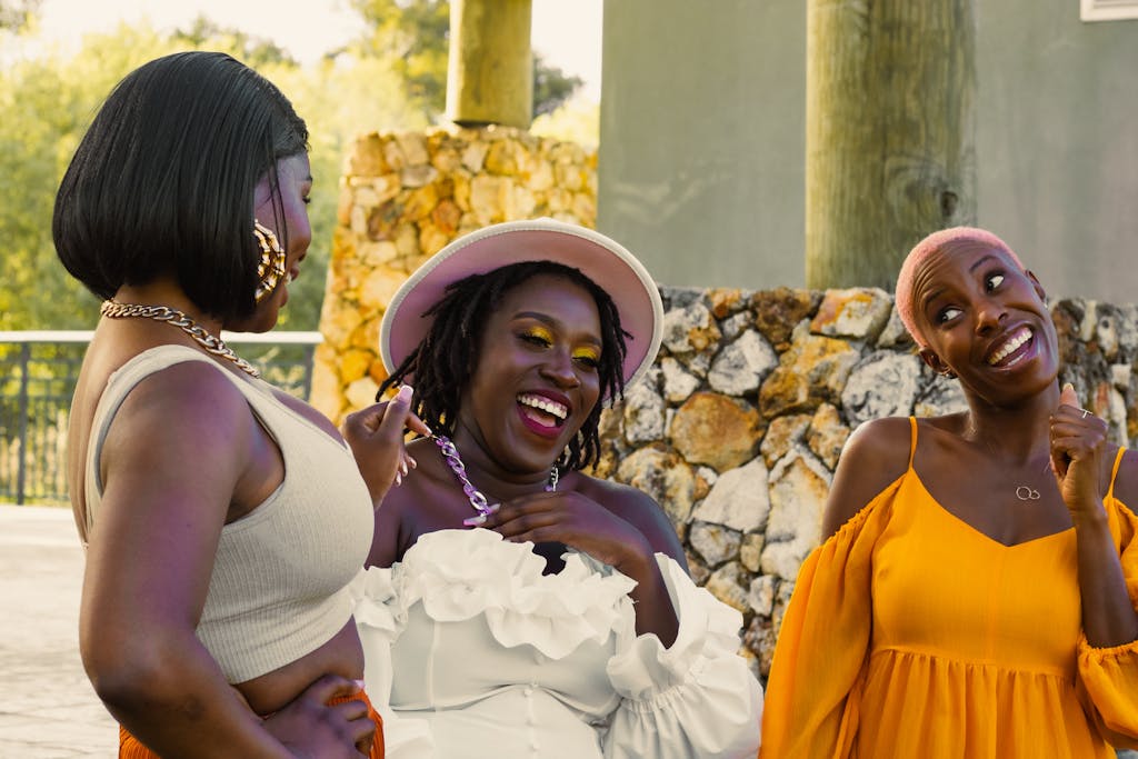 Three women laughing together outdoors, showcasing joy and friendship.